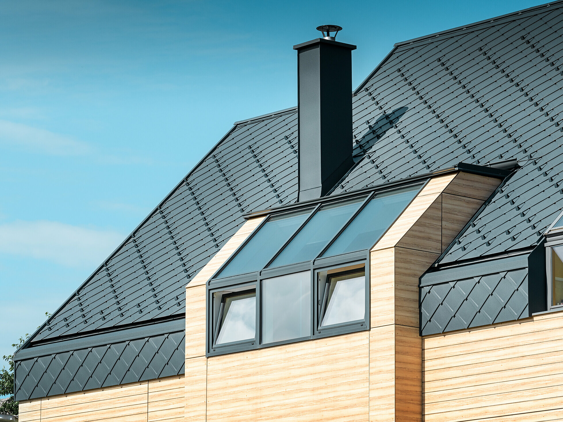 Einfamilienhaus mit Satteldach ohne Dachvorsprung mit einer Fassade in Holzoptik und einem Aluminiumdach in anthrazit