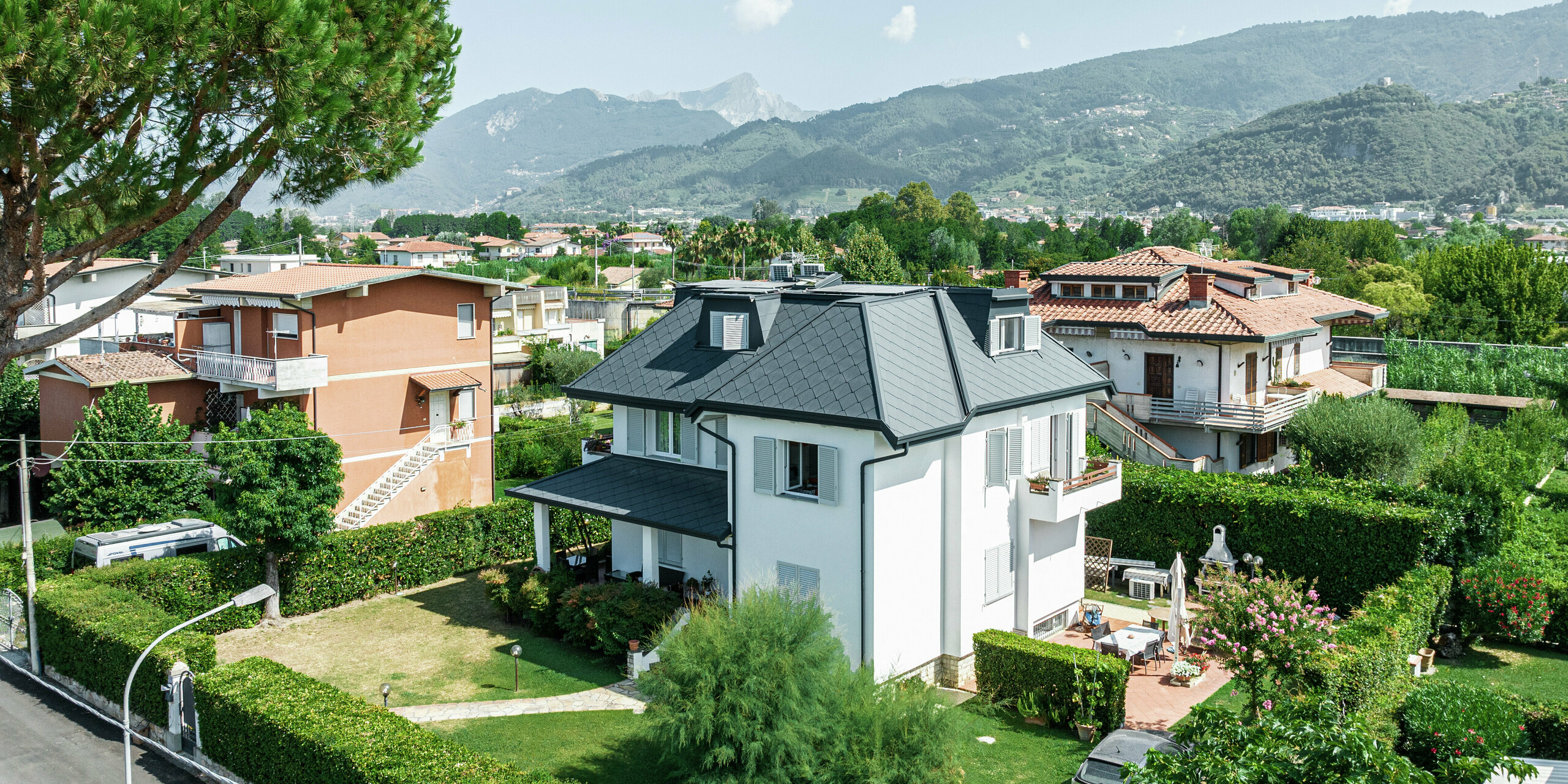 Das elegante Einfamilienhaus im italienischen Montignoso beeindruckt mit einer hochwertigen PREFA Dacheindeckung aus robustem Aluminium. Die PREFA Dachraute 44 × 44 in P.10 Steingrau sorgt für eine moderne, witterungsbeständige und langlebige Lösung. Das Aluminiumdach fügt sich harmonisch in die mediterrane Umgebung ein und bietet optimalen Schutz vor Sturm, Korrosion und UV-Strahlung. Die präzise Verarbeitung und das stilvolle Design unterstreichen die hohe Qualität der PREFA Produkte.
