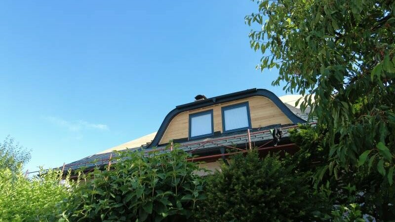 Frontale Ansicht des Hauses, das eine Hechtgaube zeigt. Für die Dachsanierung wurde die Dachschindel DS.19 in P.10 Anthrazit verwendet.