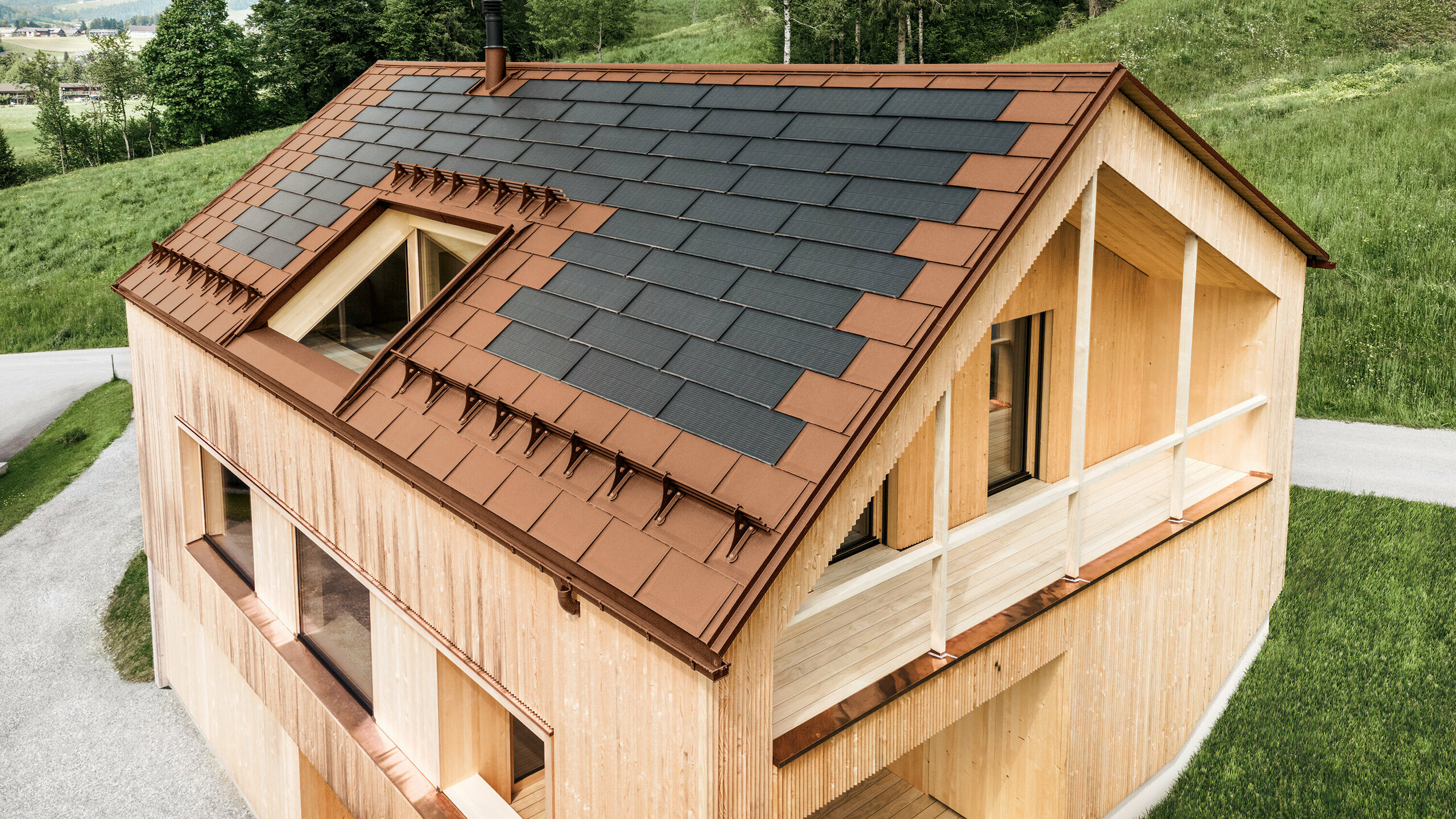 Einfamilienhaus im österreichischen Ort Egg mit der PREFA Solardachplatte und der Dachplatte R.16 in Ziegelrot, kombiniert mit einer Holzfassade