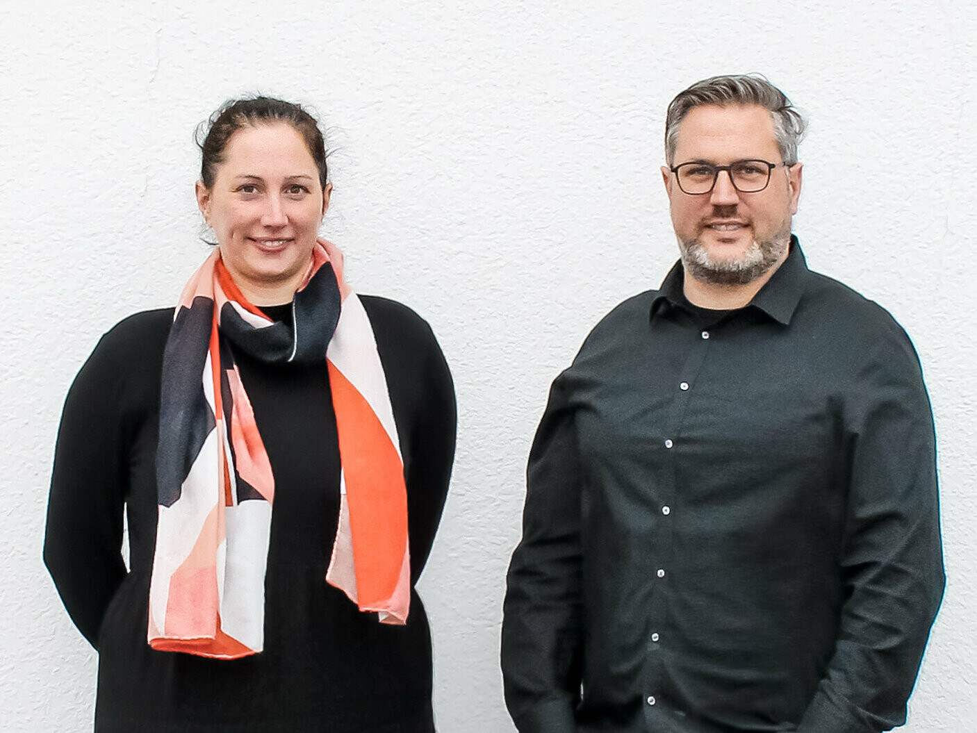 Portrait von den Geschwistern Nathalie und Marc Bodarwé von BODARWE Architektur vor einer weiß verputzten Wand.