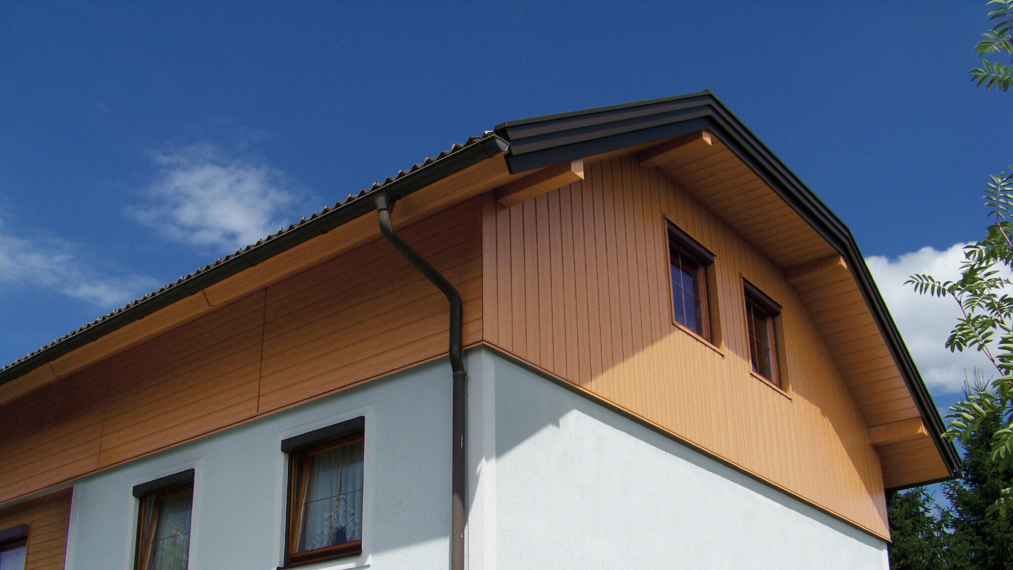 Großes Einfamilienhaus mit Krüppelwalmdach und einer Giebelverkleigung mit den PREFA Sidings in Holzoptik (Farbe Eiche natur)