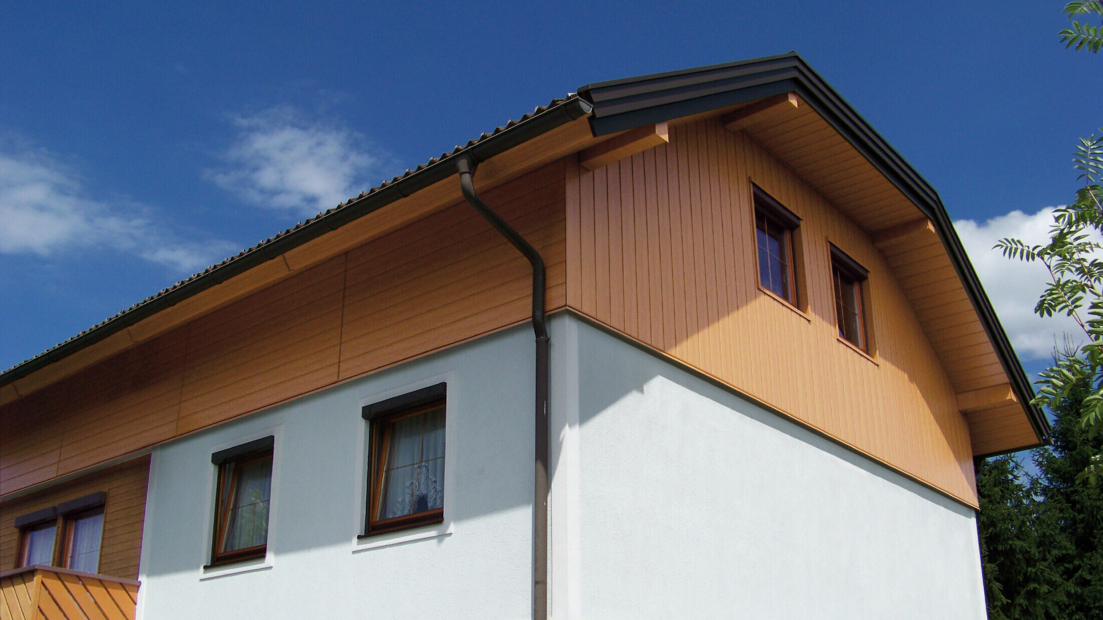 Großes Einfamilienhaus mit Krüppelwalmdach und einer Giebelverkleigung mit den PREFA Sidings in Holzoptik (Farbe Eiche natur)