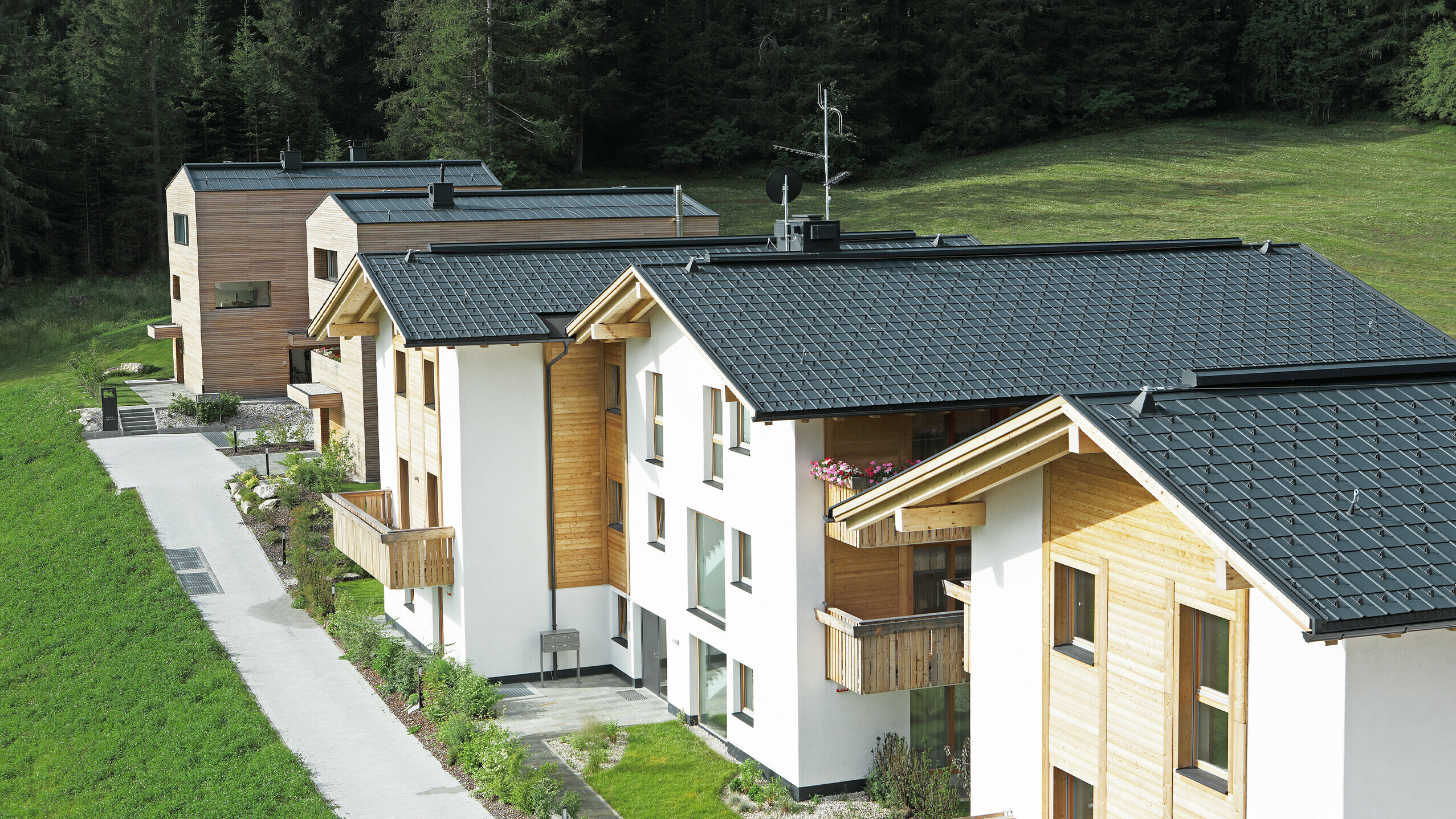 Aufnahme der fünf Wohnbauten in Corvara, eingedeckt mit der PREFA Dachplatte und Stehfalz in Anthrazit aus sturmsicherem Aluminium