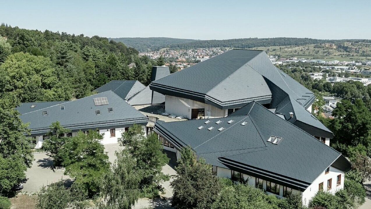 Verwinkelte Dachformen der Waldorfschule Heidenheim eingedeckt mit PREFA Dachschindeln in P.10 Anthrazit