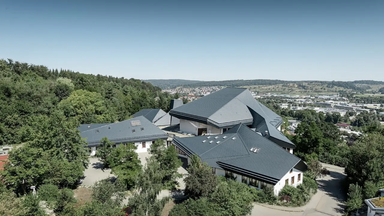 Verwinkelte Dachformen der Waldorfschule Heidenheim eingedeckt mit PREFA Dachschindeln in P.10 Anthrazit