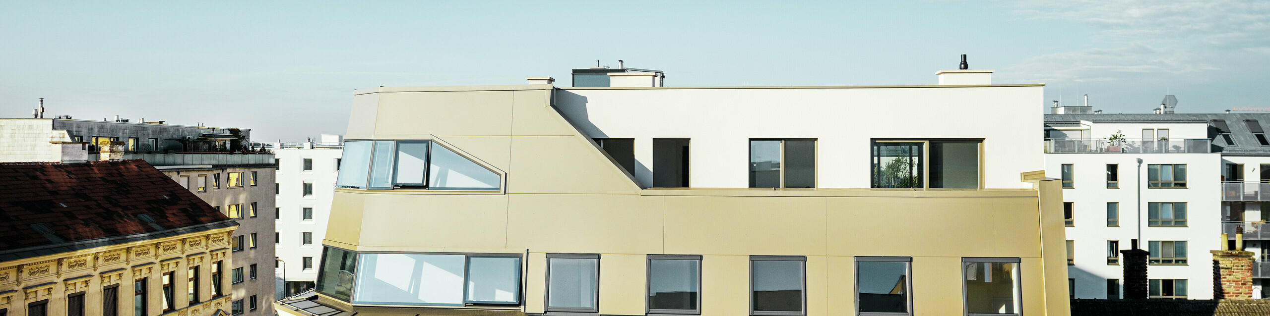 Das neue Dachgeschoss in der Schloßhofer Straße präsentiert sich mit PREFA Aluminium Verbundplatten in Bronze als architektonisch durchdachter Kontrast zum Altbau. Die Kombination aus Funktion, Ästhetik und Langlebigkeit steht für zeitgemäßes städtisches Wohnen. Die klar strukturierten Fensterachsen und die hochwertige Aluminiumfassade schaffen ein durchdachtes Zusammenspiel von Licht, Fläche und Funktionalität.