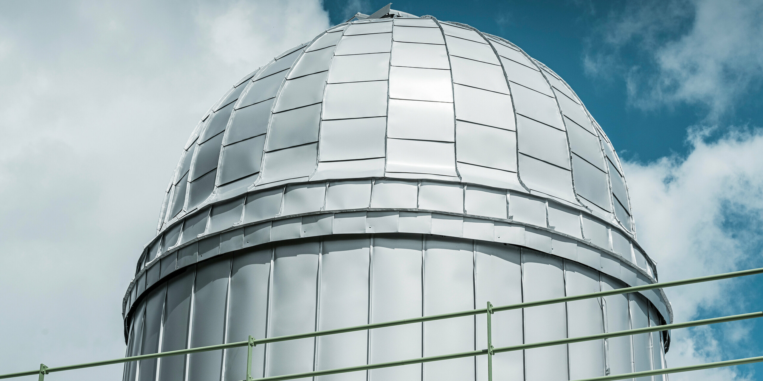 Detailansicht der strahlenden Kuppel der Sternwarte Skalnaty Pleso, umhüllt in PREFALZ in Silbermetallic. Die glänzende Aluminiumverkleidung spiegelt den blauen Himmel wider und symbolisiert die Beständigkeit gegenüber den anspruchsvollen klimatischen Bedingungen in 1.783 Metern Höhe.