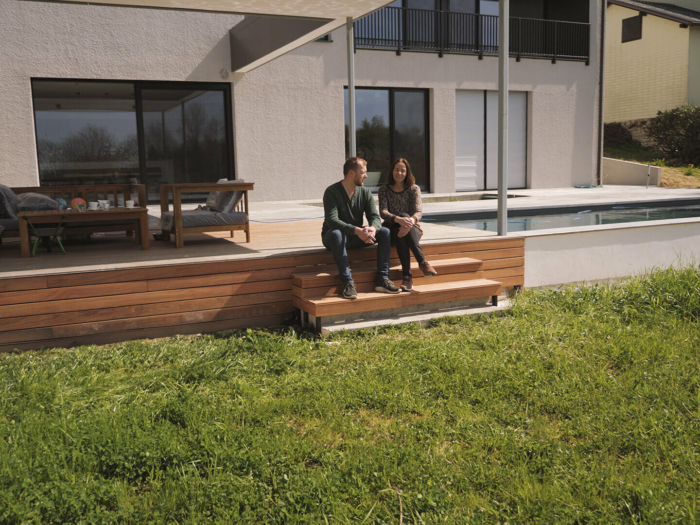 Die Familie Razenberger sitzt auf ihrer neu gebauten Terrasse, im Hintergrund ist der Pool zu sehen.