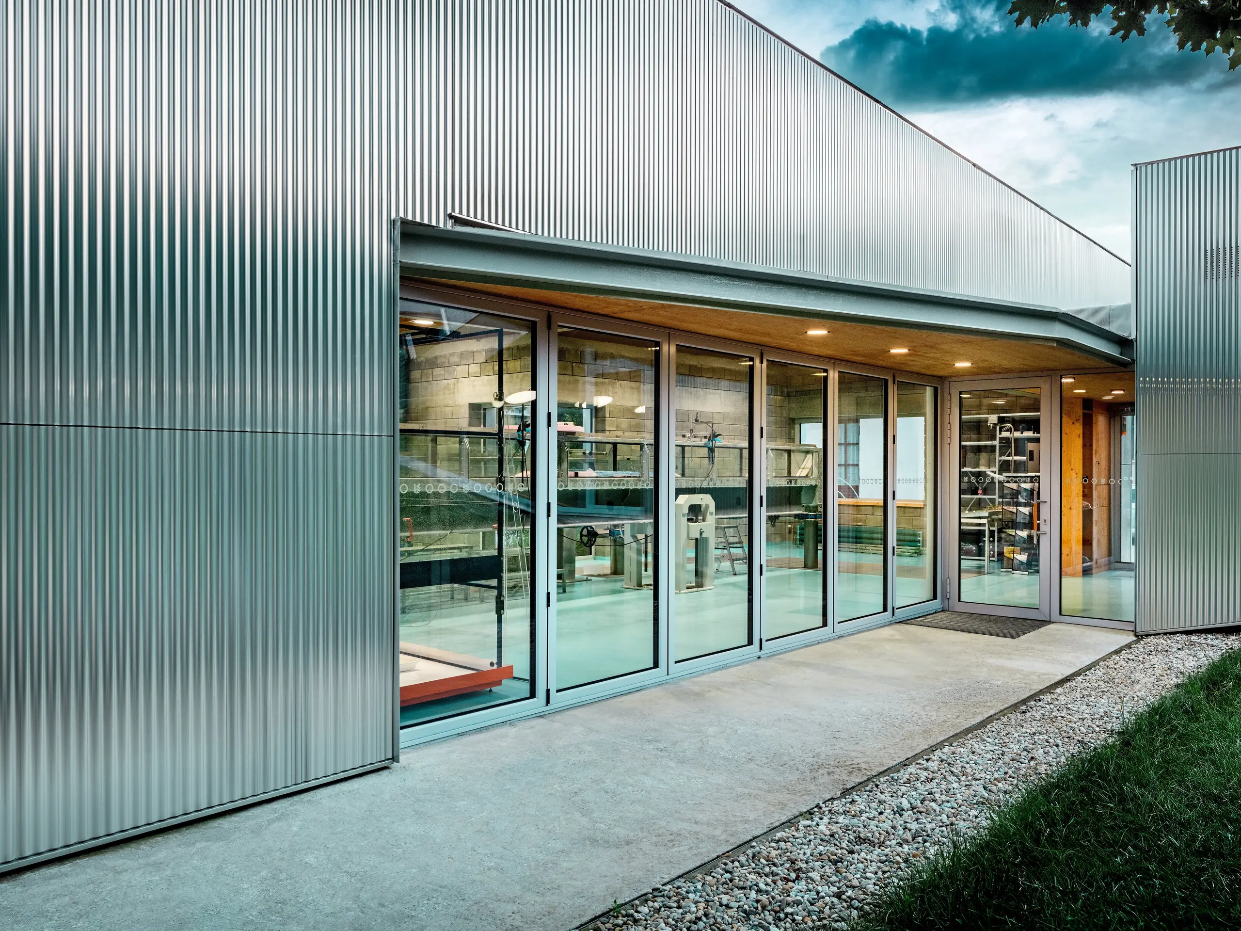 Die silbern schimmernde PREFA Aluminiumfassade mit Strangpressprofil Welle in Naturblank verleiht dem Envirocenter Nitra eine markante, moderne Optik. Vertikale Wellenstrukturen treffen auf großzügige Glasfronten, die spannende Einblicke in das Hydrauliklabor ermöglichen. Die langlebigen, witterungsbeständigen Aluminiumprofile verbinden elegante Architektur mit Funktionalität und setzen einen reizvollen Kontrast zur begrünten Außenanlage.