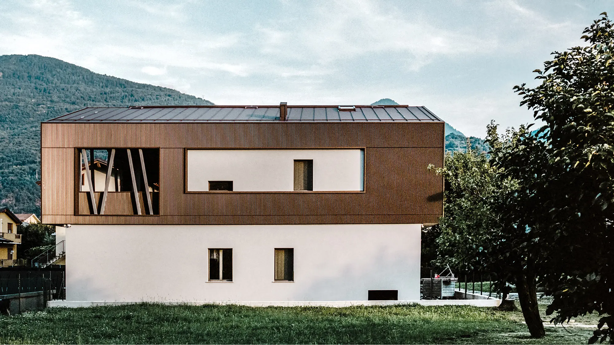 Die Villa 2B von der Seite; ihre Aluminiumhülle sieht aus, als wäre sie über die Putzfassade gestülpt.