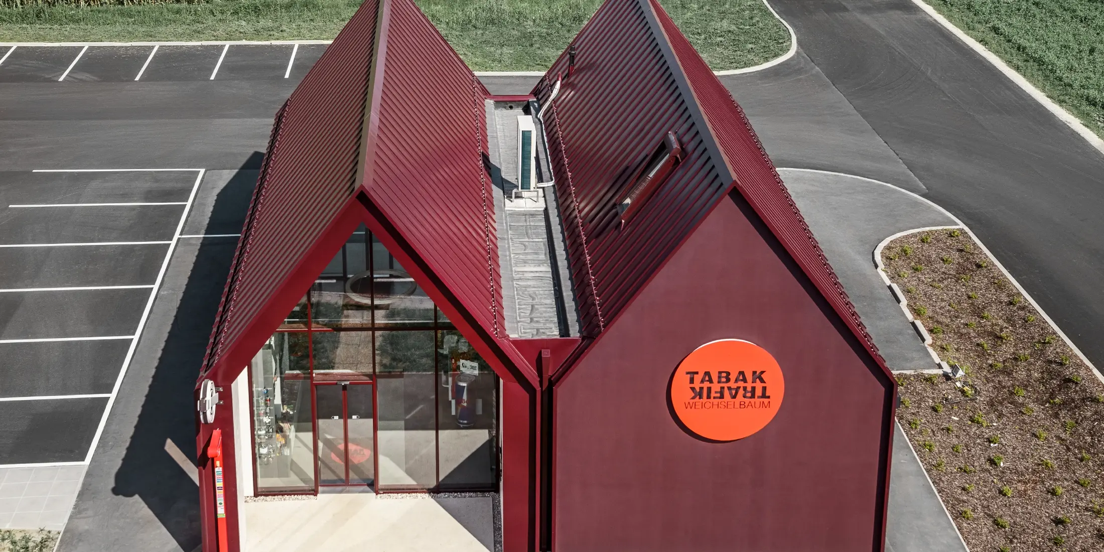 moderne Trafik mit Satteldach und ohne Dachvorsprung und einer Aluminiumhülle von PREFA als Stehfalz- und Winkelstehfalz in der Sonderfarbe schwarzrot ausgeführt