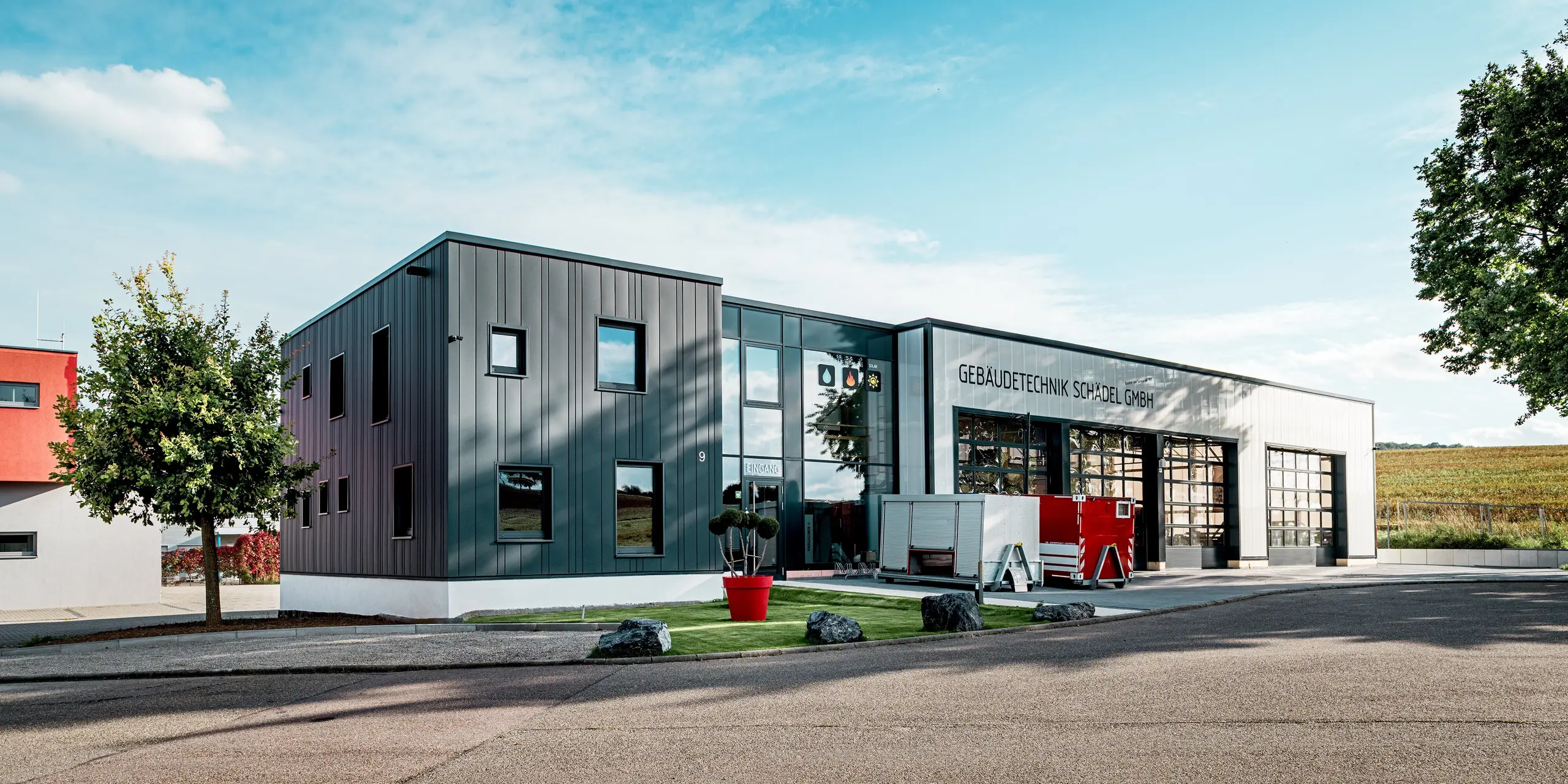 Aus der Perspektive der Zufahrt wirkt das Firmengebäude der Gebäudetechnik Schädel GmbH besonders imposant. Die anthrazitfarbenen PREFA Sidings erzeugen eine klare, strukturierte Optik, die perfekt zur modernen Industriearchitektur passt. Die Kombination mit der hellen Sockelzone und der großen Glasfront schafft starke Kontraste. Die witterungsbeständigen Aluminiumprofile sorgen für langanhaltende Ästhetik und Schutz.