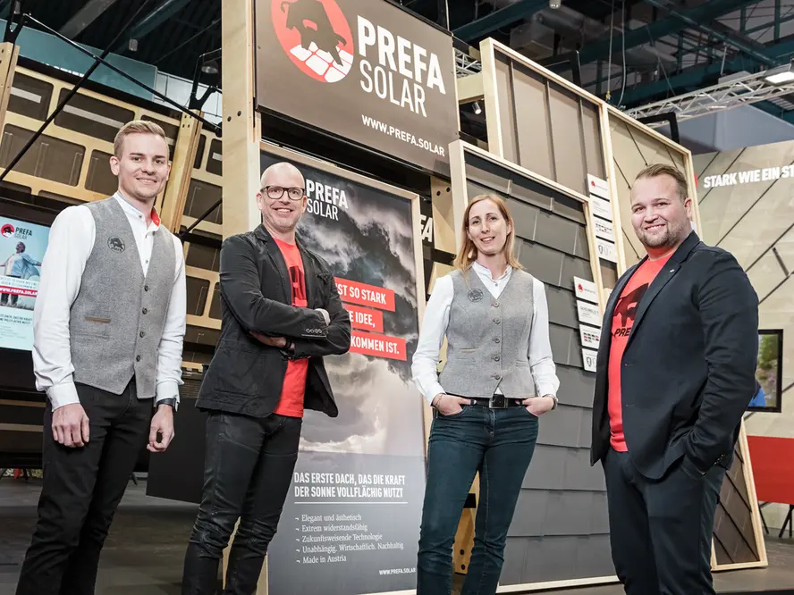 Das Entwicklerteam bestehend aus Sandra Stritzl, Jürgen Jungmair, Fabian Klaus und Jürgen Bauer vor dem Messestand für die PREFA Solardachplatte 